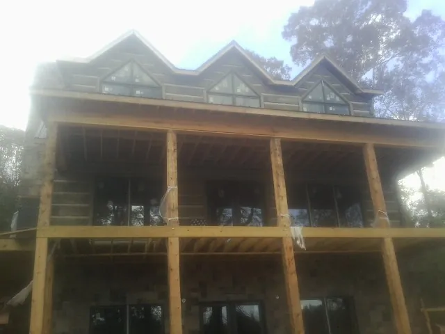 Dormers and porch framing on a large log home under construction — Roof Coating work by our crew in Spring Lake